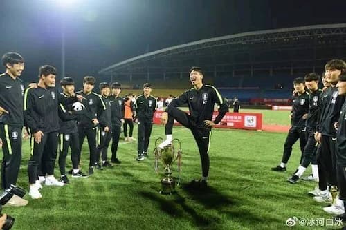 優勝トロフィーを踏む韓国のサッカー選手